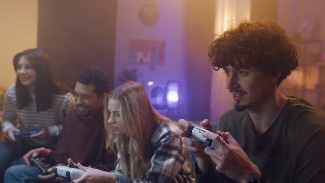 Close-up portrait of young people. Group of friends are holding joysticks and playing video games. Youth are spending time together and having fun, Multicultural diversity.