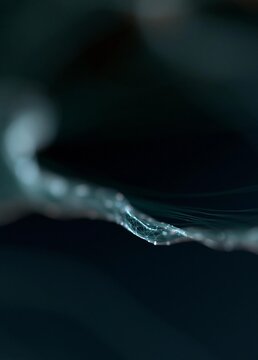 Close-up of a single drop of water on a dark background. the drop is in the center of the image, with a thin, white line extending from the bottom right corner to the top left corner.