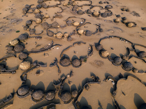 Aerial view of an abandoned village with traditional circular huts and stone enclosures in the Cholistan Desert, Punjab, Pakistan.