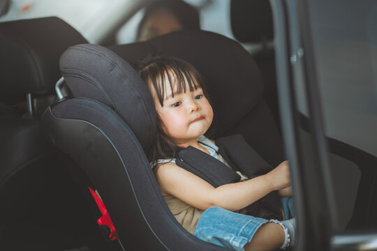 Toddler sitting securely in child safety seat inside car, family travel and road safety concept