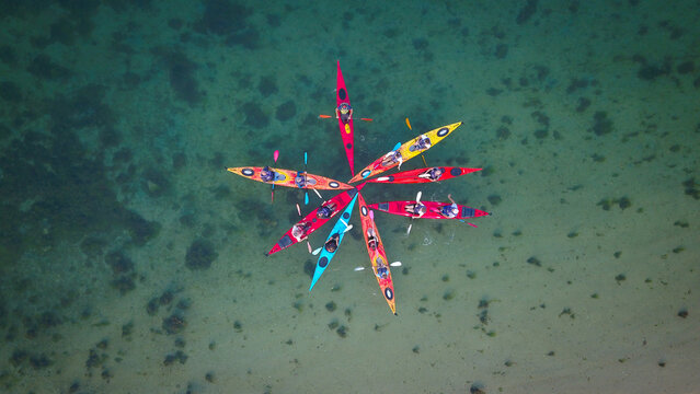 Aerial view of kayakers in a star formation in the clear shallow waters around Govean island in Sarzeau, Bretagne, France.