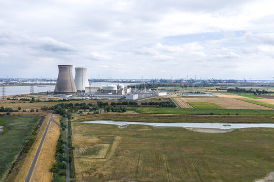 Aerial view of the Doel Nuclear Power Plant with cooling towers along the Scheldt river, surrounded by fields and infrastructure in Beveren-Kruibeke-Zwijndrecht, Vlaanderen, Belgium.