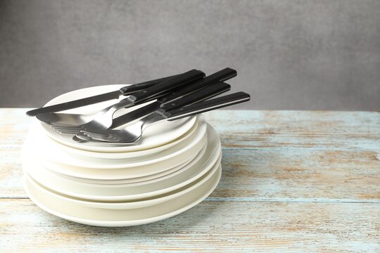Ceramic dishware and cutlery on wooden table against gray background, closeup. Space for text