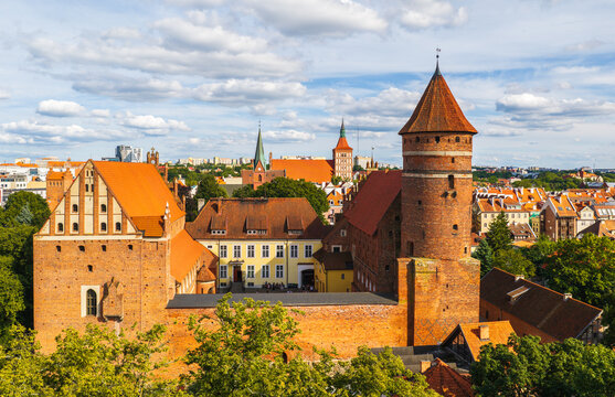 Aerial view of the historic Muzeum Warmii i Mazur w Olsztynie with its red brick tower and orange tiled roofs surrounded by city architecture in Olsztyn, Warmian-Masurian Voiv, Poland.