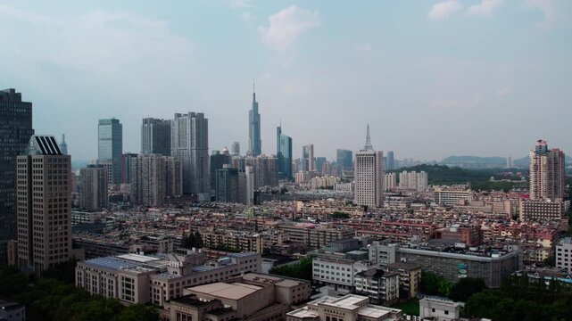 A daytime panoramic view of a dense modern city with skyscrapers and mixed buildings under a light sky.