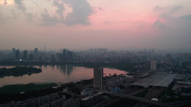 Aerial view of urban cityscape at dawn, with river, modern buildings and soft pink sky with clouds.
