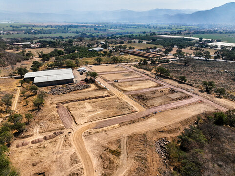 Aerial view of El Pedregal residential division with dirt roads and construction plots in the rural landscape of Tuxpan, Jalisco, Mexico.