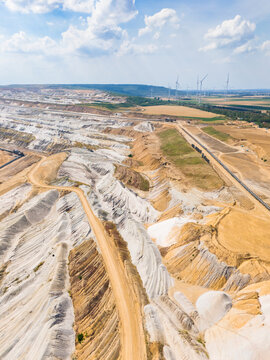 Aerial view of Hambach open pit mine showing vast lignite mining operations with terraced earth, conveyor belts, and wind turbines in Elsdorf, North Rhine-Westphalia, Germany.