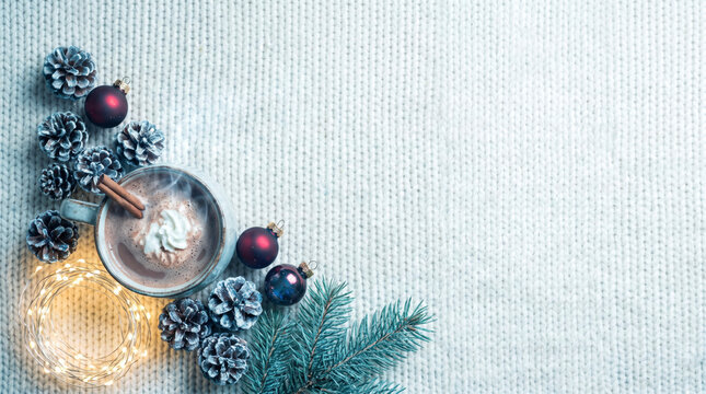 Winter cocoa flat lay with pinecones, ornaments, and fairy lights on knit copy space