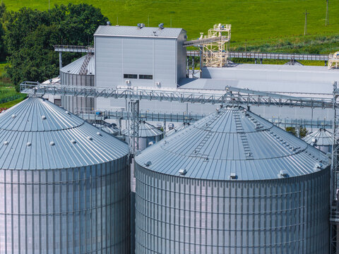 Aerial view of modern grain silos and industrial storage facilities surrounded by lush green fields, Paslek, Warmian-Masurian Voivodeship, Poland.