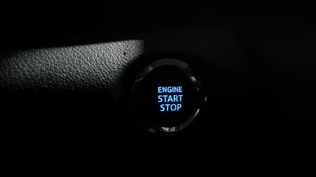 Close-up of hand pushing engine start stop button to start car