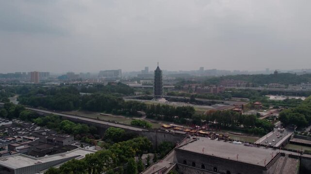 Aerial view of historic city fortifications and ancient pagoda set in a modern urban landscape with greenery.