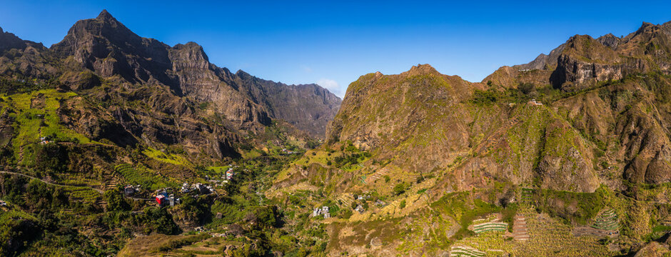Aerial view of the rugged volcanic mountains of Santo Antao, featuring lush green terraced hillsides, deep valleys, and small houses in Faja de Cima, Paul, Cabo Verde.