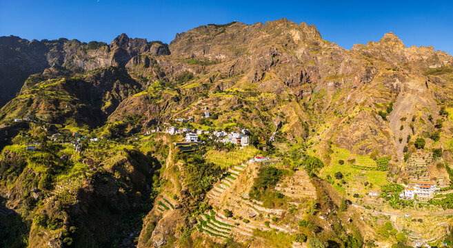 Aerial view of the mountainous Santo Antao landscape, featuring terraced fields, village houses on slopes, and lush green vegetation in Faja de Cima, Paul, Cabo Verde.