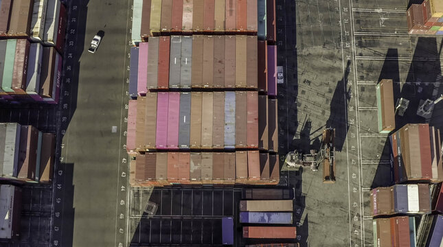 Aerial view of colorful shipping containers stacked in rows at the busy port terminal in Long Beach, California, United States.