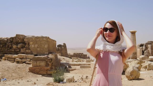 Female traveler exploring ancient Egyptian ruins near the pyramids of Giza, surrounded by historic stone structures and archaeological remains under the desert sun.