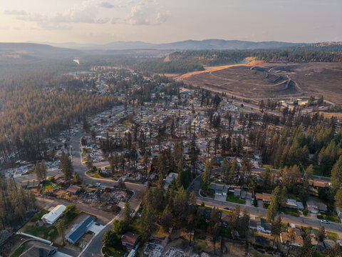 Aerial view of wildfire damage in a residential neighborhood with scorched trees and destroyed homes in Spokane, Washington, United States.
