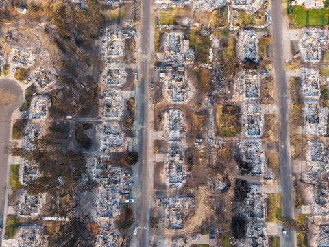 Aerial view of the aftermath of a wildfire in a residential neighborhood, showing destroyed homes, charred foundations, and scorched trees in Spokane, Washington, United States.