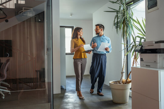 Business colleagues discussing strategy walking through office corridor