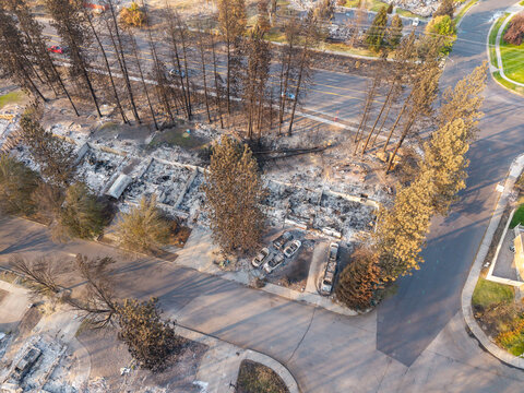 Aerial view of wildfire damage in a residential neighborhood showing destroyed homes, charred trees, and burnt vehicle remains in Spokane, Washington, United States.
