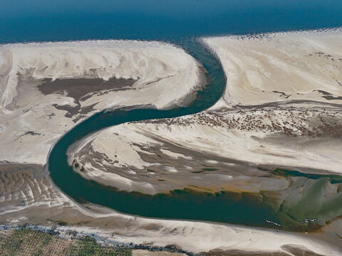 Aerial view of the winding river flowing through expansive sandbanks and sediment deposits in the rural landscape of Kushtia, Khulna Division, Bangladesh.