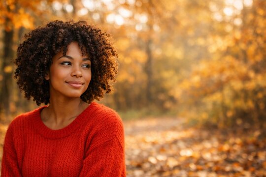 Young woman portrait in an autumn forest wearing a red sweater for cozy seasonal background and lifestyle imagery