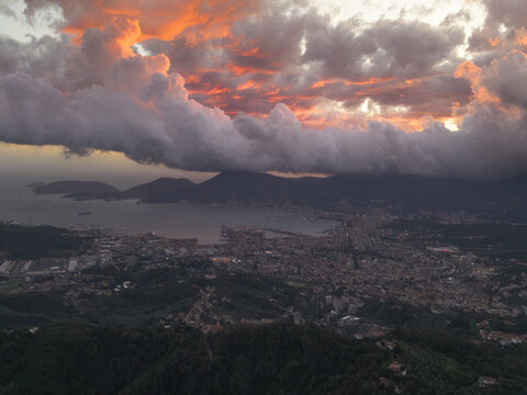 Aerial view of the town of Vezzano Ligure and the surrounding landscape near the Gulf of La Spezia under a dramatic sunset sky with heavy clouds. Vezzano Ligure, Liguria, Italy.