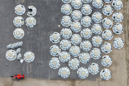 Aerial view of numerous prefabricated stainless steel storage tank roofs arranged in rows on a paved industrial site in North Holland, Netherlands.