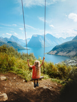 Child girl swinging with fjord and mountains view family travel in Norway, kid having fun playing outdoor active vacations hiking adventure tour in Sunnmore Alps explore beautiful travel destination