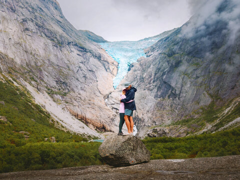 Couple in love hugging in Norway mountains with Briksdalsbreen glacier view, man and woman travel together on romantic vacation friends enjoy hiking adventure trip healthy lifestyle bonding in nature