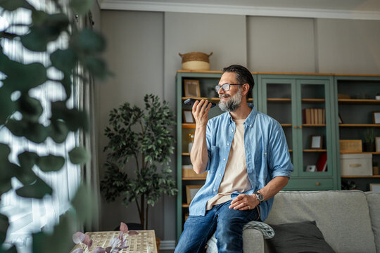 Man recording voice message on phone at home