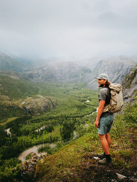 Hiker man explore Norway hiking in Rago mountains travel solo healthy lifestyle freedom active adventure summer vacations trip with backpack outdoor, male tourist enjoying river and forest foggy view