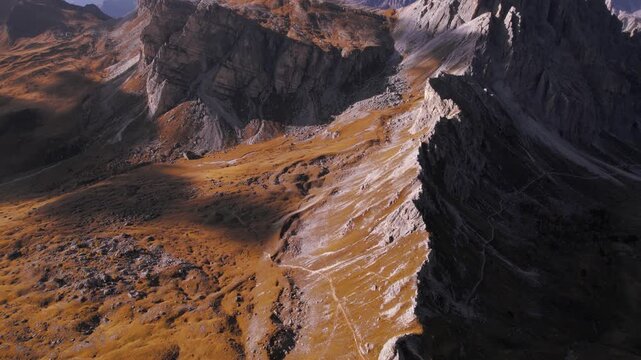 Flying over Mondeval plateau in the Italian Dolomites with dramatic light and shadow on the mountain ridge