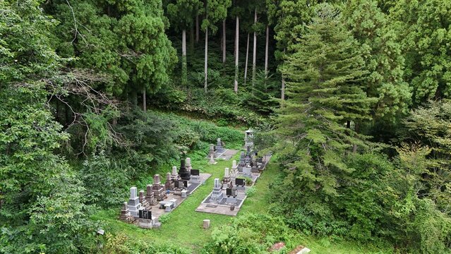 Aerial view of Ozuchi cemetery in the Kaga Higashitani Preservation District, featuring traditional stone grave markers surrounded by dense green trees Kaga, Ishikawa, Japan.