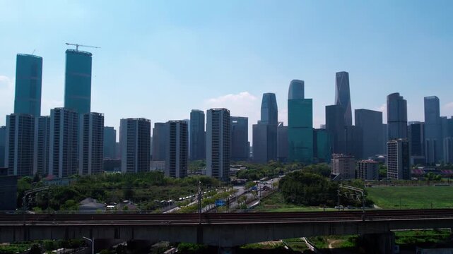 A daytime view of a modern urban skyline with skyscrapers, roads, and green spaces in a developed city area.