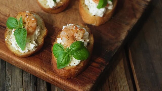 Bruschetta or crostini. Slices of toasted bread with feta, shrimp and fresh basil on wooden board.