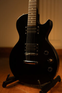 Vertical Full Shot of Solid Body Black Electric Guitar on Stand