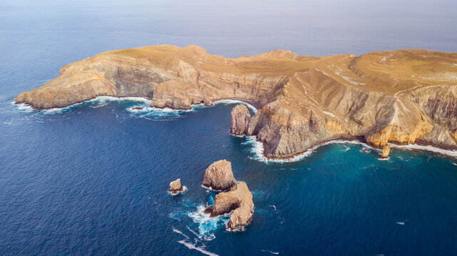Aerial view of San Benedicto Island featuring rugged volcanic cliffs, rocky sea stacks, and deep blue ocean waters in Colima, Mexico.
