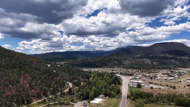 Summer aerial of small town South Fork Colorado in valley surrounded by forest along Highway 160