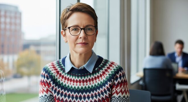 Professional woman with glasses wearing a patterned sweater in office