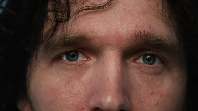 Portrait of young Caucasian man opening eyes and looking directly into camera, extreme close up. Clip is perfect for mental health campaigns or ophthalmology clinic advertisements