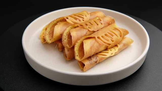 Thai Mini Pancake Roll stuffed with Quail Egg and Minced Pork ,and chili paste and shredded pork on white plate.popular street snack in Thailand call "khanom tokyo"