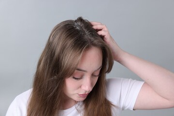 Fototapeta premium Dandruff problem. Woman examining her head on grey background