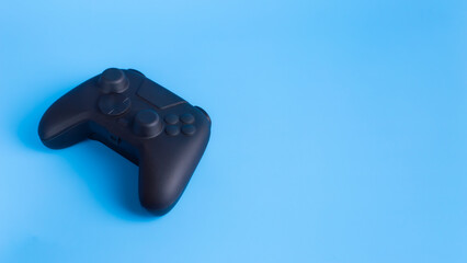 Angled black wireless gamepad controller on blue background with copy space. Ideal for gaming esports and technology advertising mockup.  © wibiwisnu