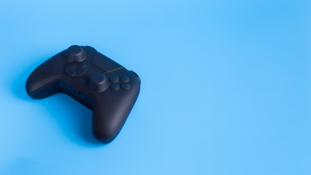 Angled black wireless gamepad controller on blue background with copy space. Ideal for gaming esports and technology advertising mockup.
