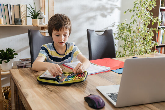 Boy learning at home with laptop and pencils