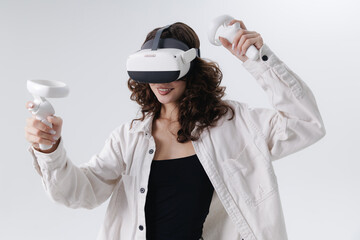 Smile Young asian female using vr headset with controllers for gaming experience with two stick controllers on white studio background © Parilov