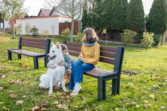 Children and white dog on a park bench