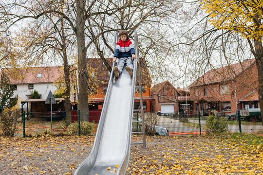 Young boy enjoying slide on autumn playground