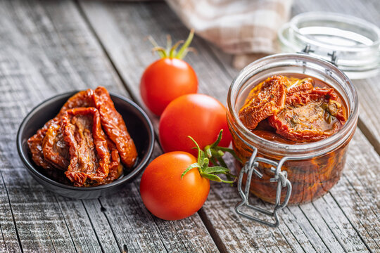 Sun-Dried Tomatoes in Glass Jar With Fresh Tomatoes on Rustic Wooden Table